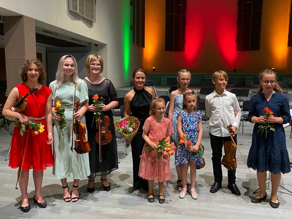 Schülerinnen und Schüler mit Geigen und Blumen nach dem Konzert