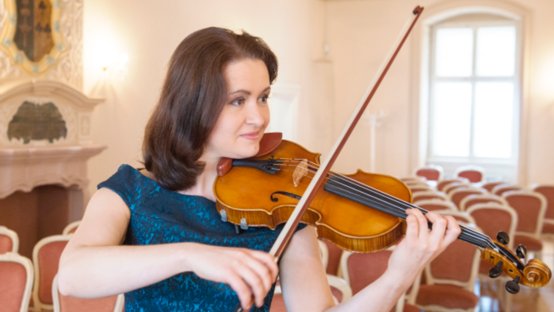 Valeria Gleim im blauen Kleid spielt Violine in einem festlichen Saal